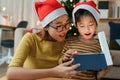 Happy Asian family with mother and daughter open Christmas present gift box together on holiday at home