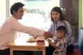 Happy asian family, with one todler spending time together inside bakery store and cafe eating cake