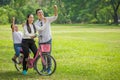 happy asian Family, parents and children riding bike hands up in park together. father ,mother ,son on bicycle having fun