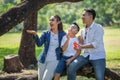 happy asian Family, parents and their children blowing soap bubbles  in park together. father, mother ,son sitting on branch of Royalty Free Stock Photo