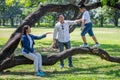 happy asian Family, parents and their children in park together. father and  mother supporting  son walking on branch of big tree Royalty Free Stock Photo