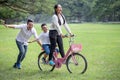 happy asian Family, parents and their children riding bike in park together. father pushes mother and son on bicycle having fun