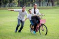 happy asian Family, parents and their children riding bike in park together. father pushes mother and son on bicycle having fun