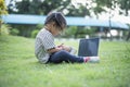 Happy asian family picnic. Daughters playing mobile phones and laptops having fun together while sitting alone on sunny day Royalty Free Stock Photo