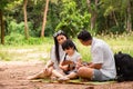 Happy asian family picnic. daugther playing ukulele with her parents Father, Mother singing song in park Royalty Free Stock Photo