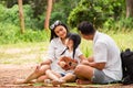 Happy asian family picnic. daugther playing ukulele with her parents Father, Mother singing song in park Royalty Free Stock Photo