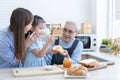 Happy Asian family preparing breakfast together. Grandmother, mother and grandchild girl spreading fruit jam on sliced bread and Royalty Free Stock Photo