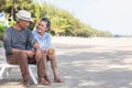 Happy Asian family, senior couple sitting on chairs with backs on beach travel vacation talking together Royalty Free Stock Photo