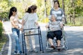 Happy asian family,senior woman, disabled grandmother with walker and wheelchair, daughter,teen granddaughter enjoying a walk in