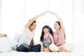 Happy asian family sitting on bed in bedroom together and making the home sign Royalty Free Stock Photo