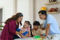 Happy Asian family sitting on chair reading a book together in the living room at home  for they education when spend their family Royalty Free Stock Photo