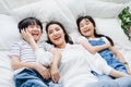 Happy Asian family smiling mother, son & daughter on bed in bedroom. Mom, son & daughter have fun together at home. Love Royalty Free Stock Photo