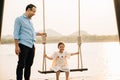 father pushing his cute daughter on a swing and both of them smiling Royalty Free Stock Photo