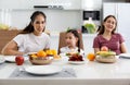 A happy Asian family spends lunch, vegetables, fruit, and dates at the table in their home. Cute little daughter having fun Royalty Free Stock Photo