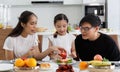 A happy Asian family spends lunch, vegetables, fruit, and dates at the table in their home. Cute little daughter having fun Royalty Free Stock Photo