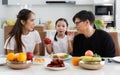 A happy Asian family spends lunch, vegetables, fruit, and dates at the table in their home. Cute little daughter having fun Royalty Free Stock Photo