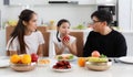 A happy Asian family spends lunch, vegetables, fruit, and dates at the table in their home. Cute little daughter having fun Royalty Free Stock Photo