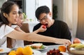 A happy Asian family spends lunch, vegetables, fruit, and dates at the table in their home. Cute little daughter having fun Royalty Free Stock Photo