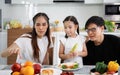 A happy Asian family spends lunch, vegetables, fruit, and dates at the table in their home. Cute little daughter having fun Royalty Free Stock Photo