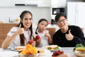 A happy Asian family spends lunch, vegetables, fruit, and dates at the table in their home. Cute little daughter having fun Royalty Free Stock Photo