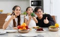 A happy Asian family spends lunch, vegetables, fruit, and dates at the table in their home. Cute little daughter having fun Royalty Free Stock Photo