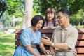 Happy asian family of three having fun watching a phone together in the summer outdoors at the park. Royalty Free Stock Photo