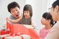 Happy Asian family unwrapping a gift box.