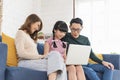 Happy Asian family using computer laptop together on sofa at home living room Royalty Free Stock Photo