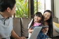 Happy Asian family using tablet laptop technology together on sofa in living room. Royalty Free Stock Photo