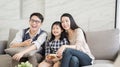 Happy asian family watching tv together on sofa in living room. family and home concept. Royalty Free Stock Photo