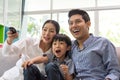 Happy asian family watching tv together on sofa in living room. family and home concept. Royalty Free Stock Photo