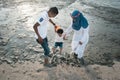 Happy asian family wearing casual and playing with mud at the muddy beach