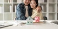 Happy asian family young couple love hand . piggy bank to save and model home for saving money to buy for new home Royalty Free Stock Photo