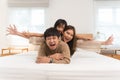 Happy Asian family, young father, mother, cute daughter lying together on bed in bedroom at home. Little girl having fun playing Royalty Free Stock Photo