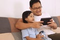 Happy Asian father and baby girl daughter looking at tablet mobile phone, family enjoys quality time Royalty Free Stock Photo