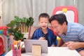 Happy Asian father and son with tablet computer are making video call to mother or relatives at home, Family having fun making Royalty Free Stock Photo