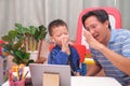 Happy Asian father and son with tablet computer are making video call to mother or relatives at home, Family having fun making Royalty Free Stock Photo