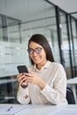 Happy Asian female employee using cell phone working in office. Royalty Free Stock Photo