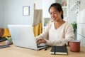 Happy Asian female entrepreneur working using laptop. Smiling Chinese woman working with computer at home office. Royalty Free Stock Photo