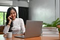 Happy Asian female freelancer in her home office, on the phone with her client Royalty Free Stock Photo