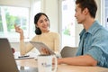 Happy Asian female having a good conversation with her male colleague while working together Royalty Free Stock Photo