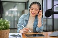 A happy Asian female radio host is interviewing a guest over the phone while broadcasting Royalty Free Stock Photo