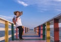 Happy Asian female tourist taking selfie with smartphone on rainbow wooden bridge at sea viewpoint Royalty Free Stock Photo