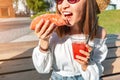 Asian girl eating taco outside and drinking beverage. Mexican fastfood cuisine. Tasty and spicy snack in park Royalty Free Stock Photo