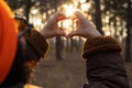 Young woman making a heart shape with her hands in the forest with sunset. Royalty Free Stock Photo