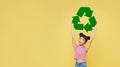 Happy Asian girl hand holding recycle symbol on yellow background. eco friendly and reusing concept