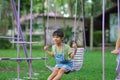 Happy Asian girl having fun playing in the playground during summer. Cute little girl swinging in the playground with a smile and