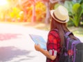 Happy Asian girl holding map with backpack in the road and forest background, Royalty Free Stock Photo