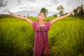 Happy Asian girl raising arms in green rice field, countryside o