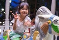 Happy Asian girl riding on a horse merry go round.